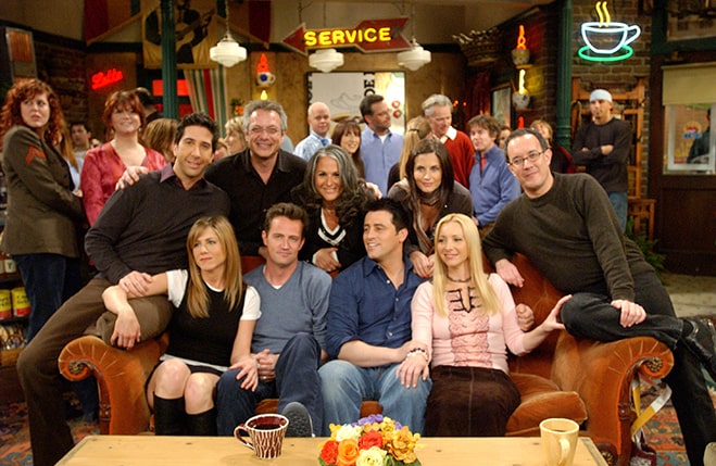 friends cast along with directors sitting on orange couch